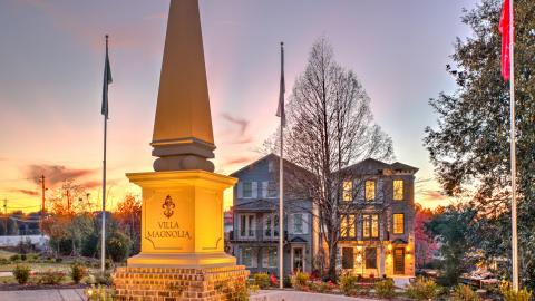 A twilight image of two homes and an obelisk at sunset. 