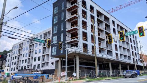 A large apartment complex being built along a busy street in Atlanta, with blue skies above. 