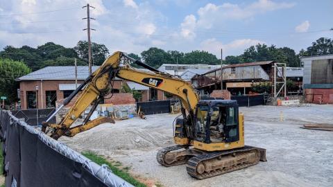 A backhoe and many old buildings at a construction site in Atlanta, under blue skies. 