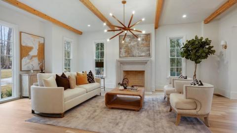 The living room of an elegant manor house in Atlanta with white walls and beams on the ceiling. 