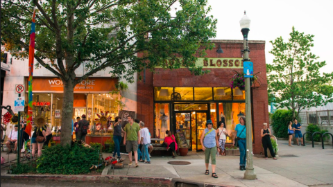 A row of shops with a lot of people milling about in front of them. 