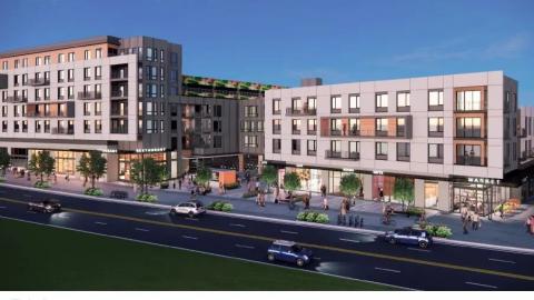 A large new mixed-use development shown under blue skies next to a busy street. 