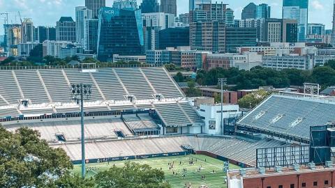 A view of a football stadium from above with Midtown Atlanta beyond. 