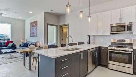 Inside a very white brand-new condo in Atlanta's midtown with stainless appliances and views of many buildings. 