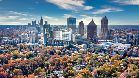 An aerial shot of a large city in autumn colors, with blue skies and clouds overhead. 