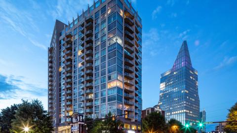 A photo of a glass and concrete high rise against evening skies in the Buckhead area of Atlanta. 