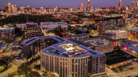 A photo of a large gray new apartment building in Atlanta with the city shown beyond.