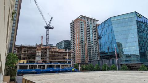 A photo of a new tower under construction under gray skies in Midtown Atlanta near glassy buildings.