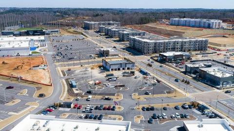 An aerial photo of a giant shopping center under blue skies with woods in the distance. 