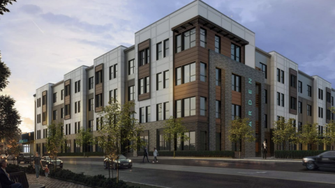 A rendering of a large new apartment building under grayish skies with cars driving by.