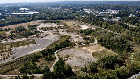 A photo of a large industrial site with many trees around the edge and parking lots in the middle.