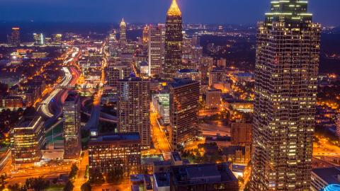 An image of Atlanta's skyline at night under blue-purple clouds. 