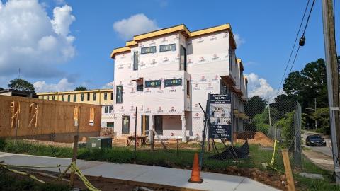 A townhome project being built under blue skies next to a busy road in Atlanta. 