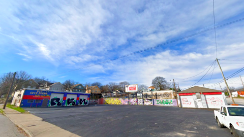 A graffiti covered auto business and garage under blue skies with a large road beside it in Atlanta.