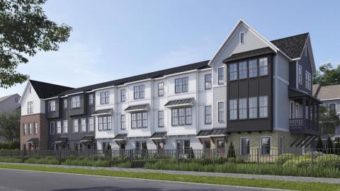 A row of townhomes shown in a rendering on a street under blue skies. 