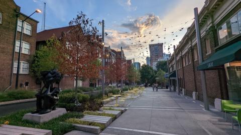 A new plaza under a sunset in Midtown Atlanta with yellow seating and a statue. 