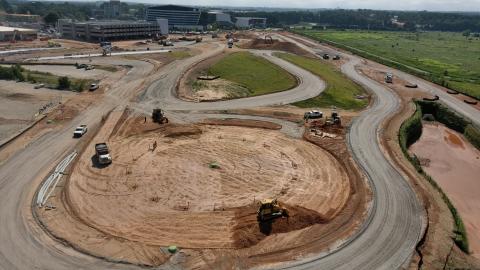 A photo of a new racetrack being built next to Porsche's Atlanta Headquarters under blue skies near a green field. 