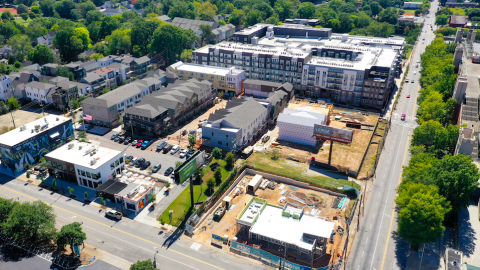 An aerial photo of new construction with apartments and businesses around a busy street near green trees in Atlanta. 