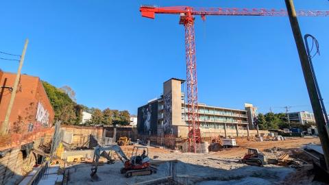 A construction site with footings and concrete and a crane above under a blue sky in Atlanta. 