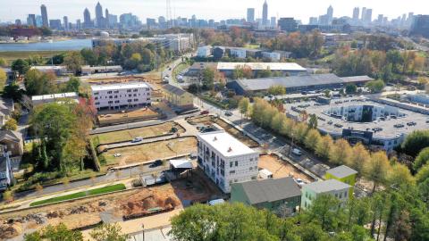 An aerial photo of a large home project being built among many buildings with the city of Atlanta skyline in the distance. 