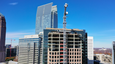 A construction photo of a tall glass and stone building in Atlanta under bright blue skies. 