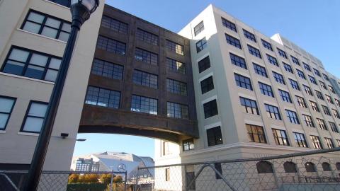 A photo of an old building under blue skies in white in downtown Atlanta, with new apartments with white walls inside. 