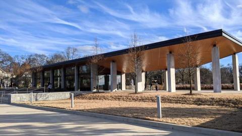 A photo of a new modern building under blue skies near a large field. 