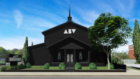 A rendering of a large church building under blue skies painted black near green trees. 
