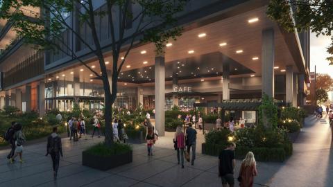 A rendering of a new office building with many plants and lights in front.