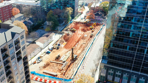An aerial photo of a large construction site between many glassy buildings. 