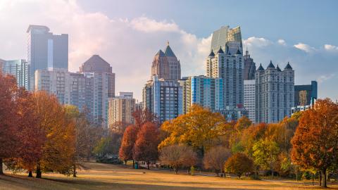 A photo of a skyline in a park under blue skies with many autumn colors all around it. 