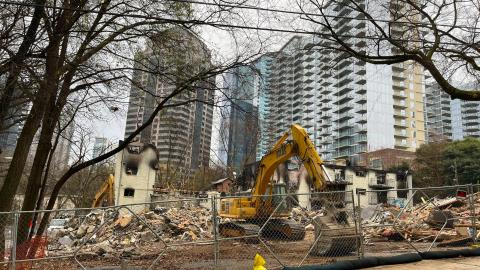 A photo of demolition of many small buildings with glassy skyrises around them.