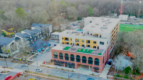 An aerial photo of a large new condo building with brick front and a green roof.