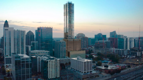 A rendering showing a very tall new building under blue skies with many buildings around it in Atlanta.