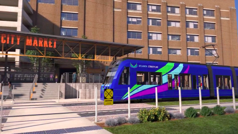 A rendering of a bluish purple Atlanta streetcar near a huge brick building under blue skies. 