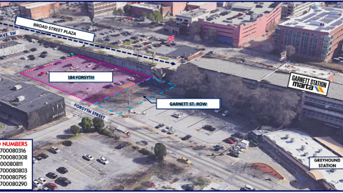 A view of a large parking lot and plaza next door in downtown Atlanta with a wide street and train tracks next door.