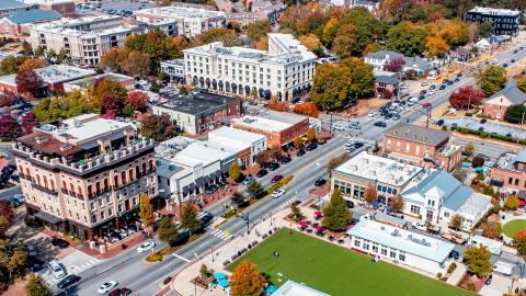 An aerial photo of a large suburban city under blue skies with many greenspaces. 