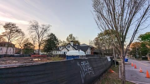 A construction site under blue purple skies with many homes and trees around. 