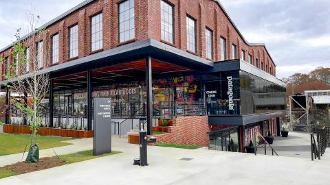 A photo of a new red brick building with a Patagonia store at the bottom and tiny trees beside it. 
