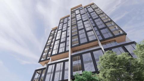 A rendering showing a glassy new building with black-trimmed windows and a large parking deck under gray-blue skies. 