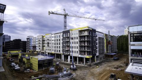 A photo of a large development with a number of buildings under construction under gray skies. 