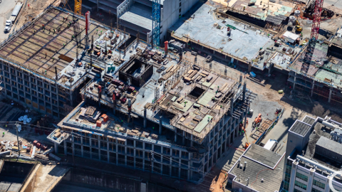 A photo of a large construction site with two buildings surrounded by many cranes.