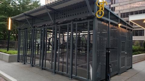 An image showing a gray cage-like structure for bicycles in the heart of Midtown Atlanta. 