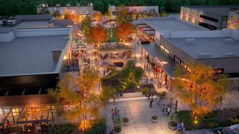 An image of a large lawn space surrounded by numerous stores and restaurants in a shopping center.