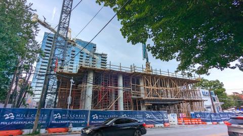 A photo of a new tower building of concrete and wood rising on a busy Atlanta street under a crane.