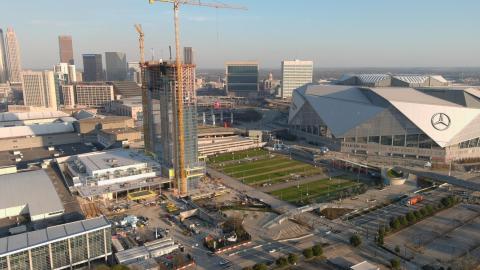 A photo of a large hotel being built beside a large field and angular stadium in Atlanta. 