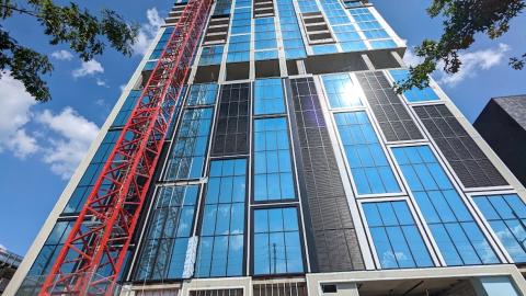 A new high-rise tower under blue skies with blue glass and white and metal panels with views across Atlanta. 
