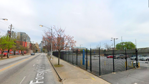 An image showing an empty lot with a wide street and city in the background. 