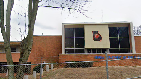 An image of a brick and glass older structure that's being torn down by heavy equipment.