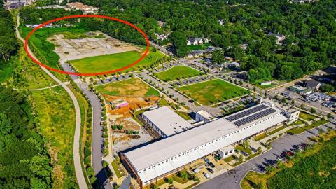 An image of a huge swath of land next to a walking and biking trail with many trees around.